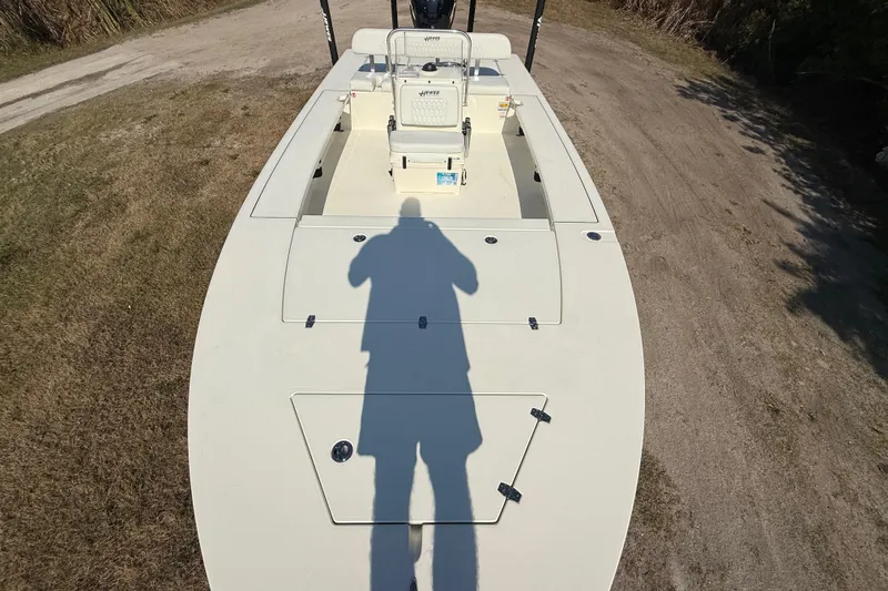 Slide: The Image of 2026 Hewes 21 REDFISHER boat on land, shadow of person visible on deck. - 17