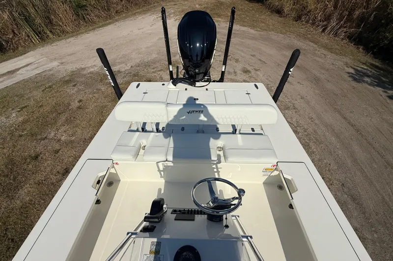 Slide: The Image of 2026 Hewes 21 REDFISHER boat interior with steering wheel and seating, parked on grassy terrain. - 21