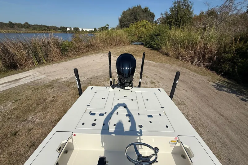 Slide: The Image of 2026 Hewes 21 REDFISHER boat on a grassy lakeside, featuring a sleek design and powerful engine. - 22