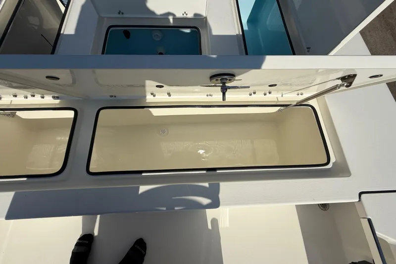 Slide: The Image of 2026 Hewes 21 REDFISHER boat storage compartments, open and empty, with sunlight casting shadows. - 24