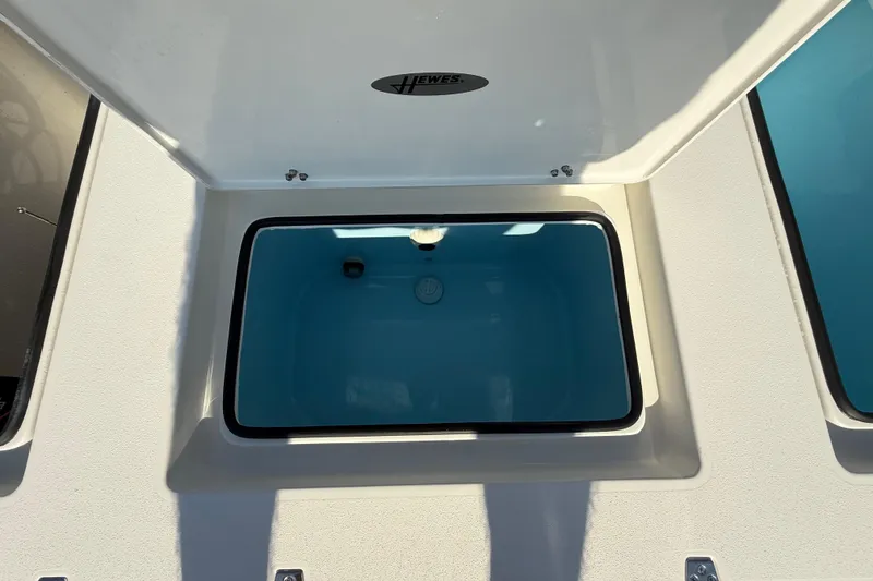 Slide: The Image of 2026 Hewes 21 REDFISHER boat storage compartment with open lid, showcasing interior space. - 28