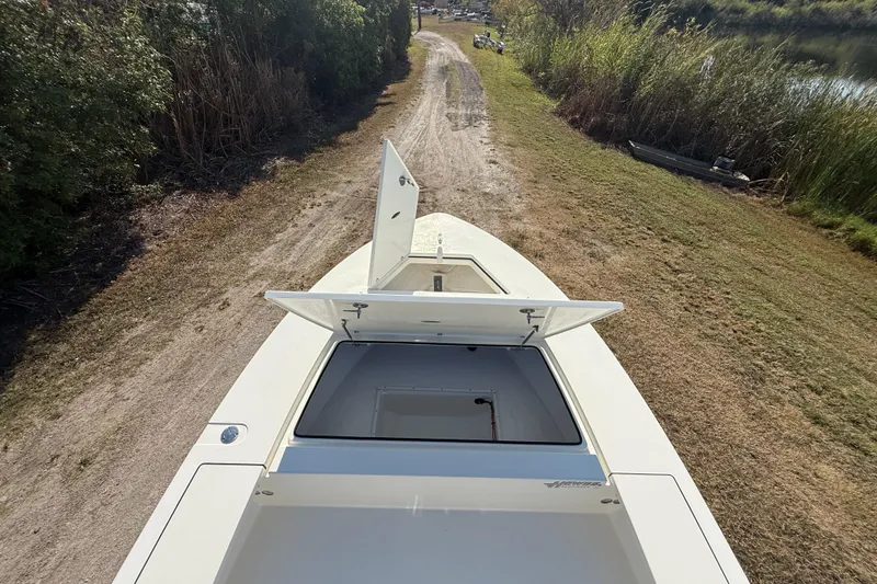 Slide: The Image of 2026 Hewes 21 REDFISHER boat with open storage compartments on a grassy path. - 32