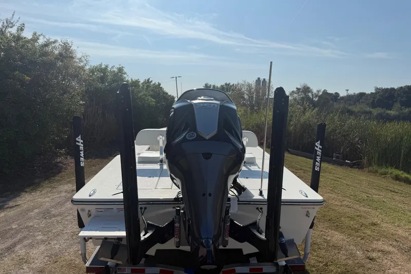 Slide: The Image of 2026 Hewes 21 REDFISHER boat with powerful outboard motor, parked on grassy area. - 4