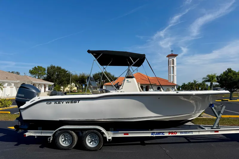 Slide: The Image of 2023 Key West 239 FS boat on trailer, parked outdoors under clear blue sky. - 4