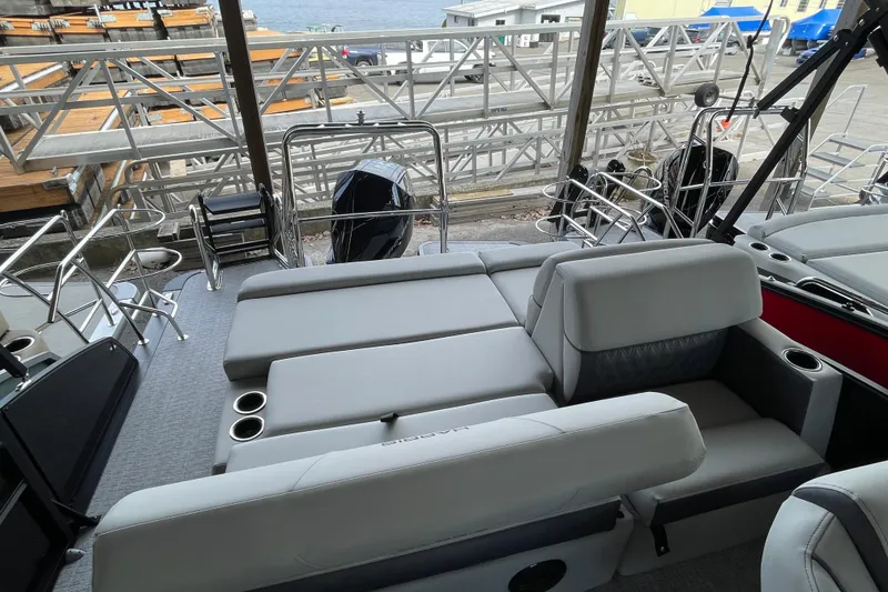 Slide: The Image of 2026 Harris Cruiser 230 boat interior with plush seating and cup holders, dockside view. - 13