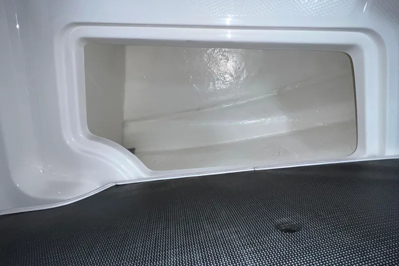 Slide: The Image of Storage compartment in a 2021 Chaparral 21 SSi boat, featuring a sleek white interior. - 18