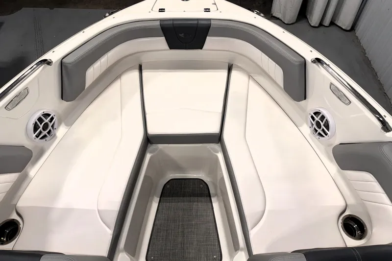 Slide: The Image of 2021 Chaparral 21 SSi boat interior with white and gray seating, cup holders, and speakers. - 2