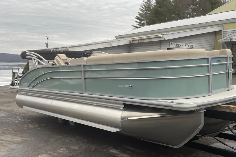 The Image of 2026 Harris Cruiser 230 pontoon boat at a marina, featuring sleek design and beige seating. - 0