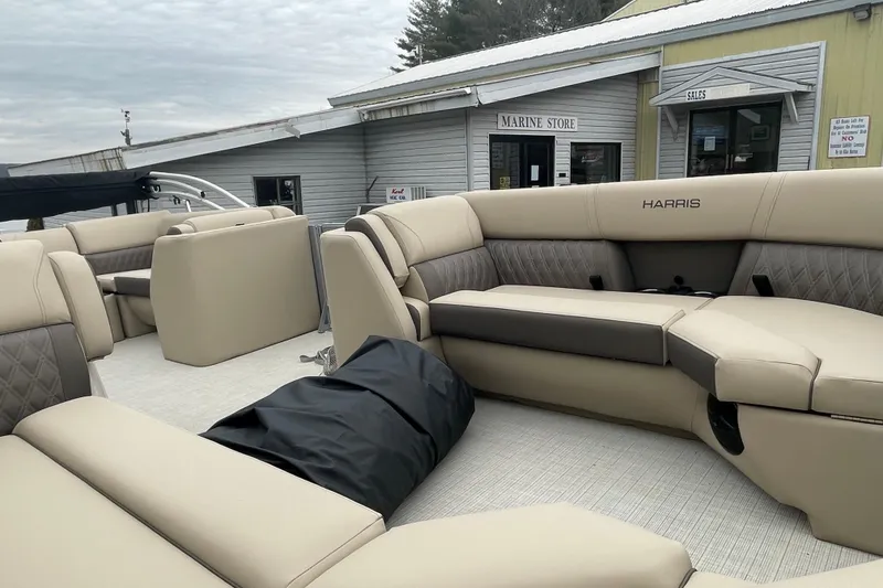 Slide: The Image of 2026 Harris Cruiser 230 pontoon boat interior with beige seating at a marine store. - 12