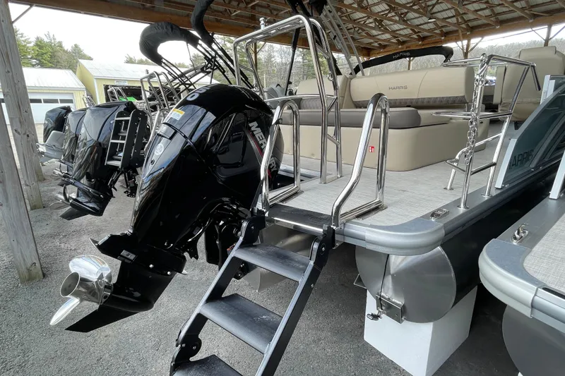 Slide: The Image of 2026 Harris Cruiser 230 pontoon boat with Mercury outboard engines under a shelter. - 16