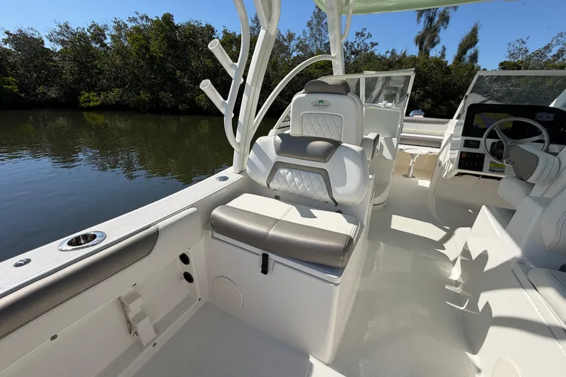 Slide: The Image of 2022 World Cat 255 DC boat interior with seating and steering wheel, near water and trees. - 14