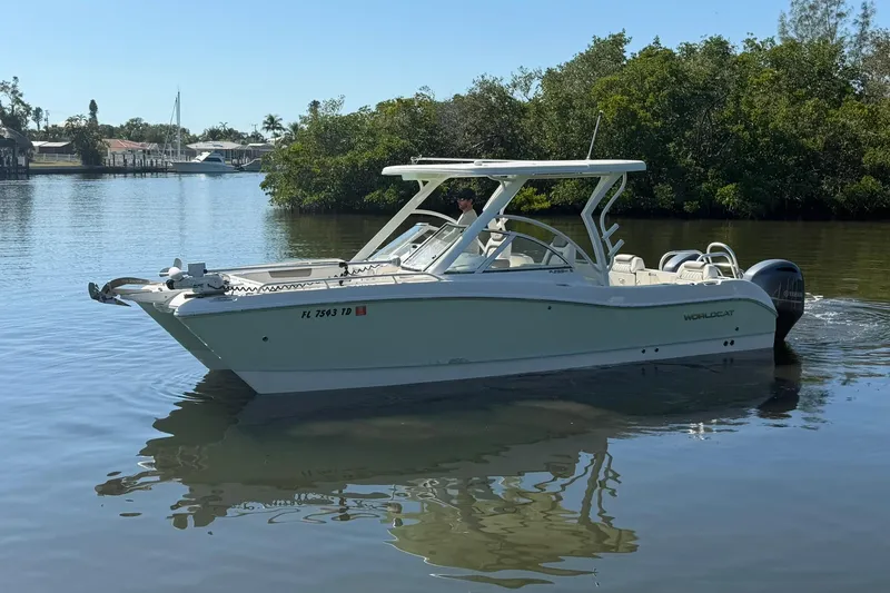 Slide: The Image of 2022 World Cat 255 DC boat cruising on a calm river with lush greenery. - 4