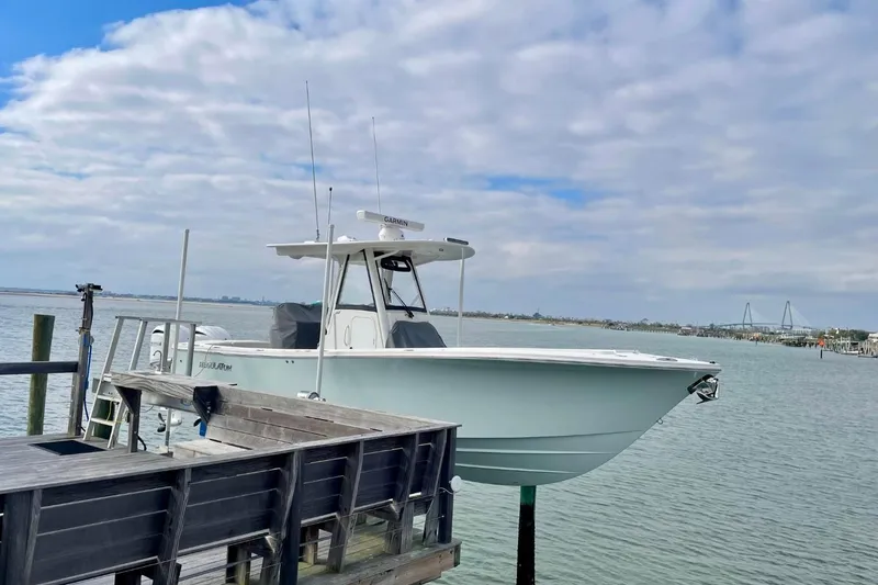 Slide: The Image of 2023 Regulator 28 Forward Seating boat docked by the water under a cloudy sky. - 3