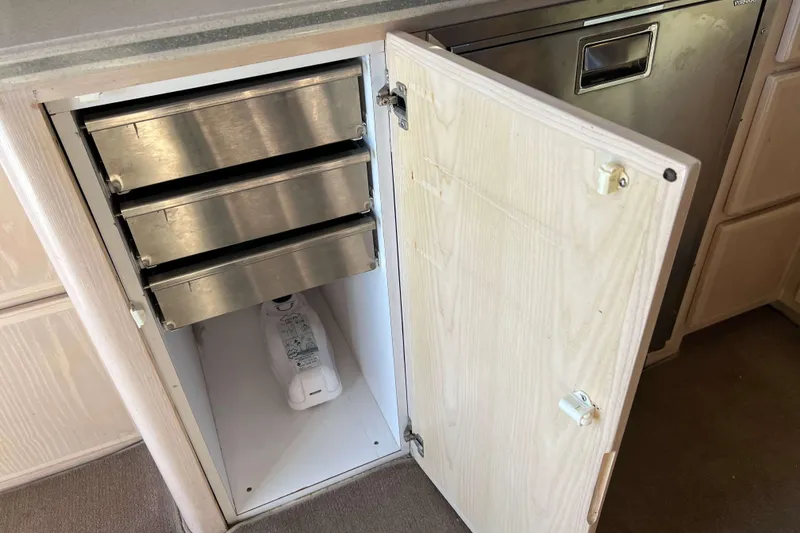 Slide: The Image of Open cabinet with metal drawers and a gallon jug inside, on a 2003 Henriques Yachts 35 Sportfisherman. - 26