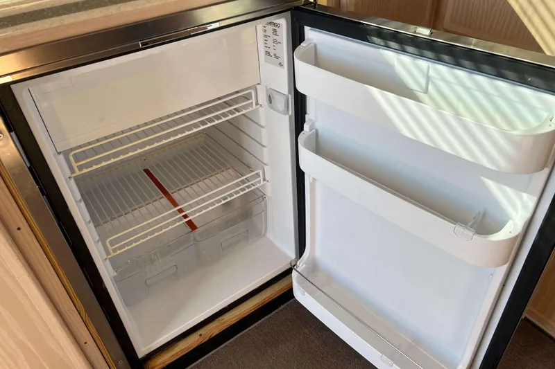 Slide: The Image of Open refrigerator inside 2003 Henriques Yachts 35 Sportfisherman, showing empty shelves and door compartments. - 27
