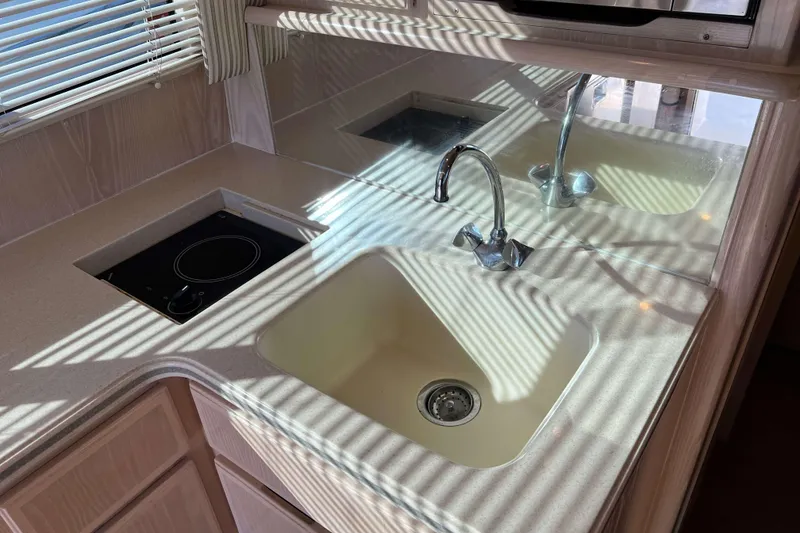 Slide: The Image of 2003 Henriques Yachts 35 Sportfisherman kitchen with sink and stovetop, sunlight through blinds. - 29