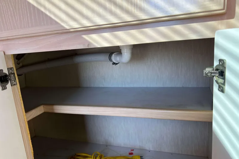 Slide: The Image of Open cabinet interior on 2003 Henriques Yachts 35 Sportfisherman, showing plumbing and storage space. - 30