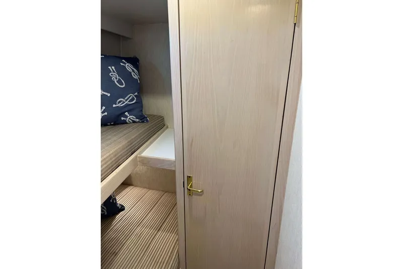 Slide: The Image of 2003 Henriques Yachts 35 Sportfisherman cabin interior with wooden door and nautical-themed bedding. - 38