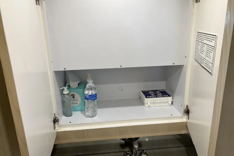 Slide: The Image of Open cabinet with first aid kit, water bottle, tissues, and sanitizer on a Henriques Yachts 35 Sportfisherman. - 45