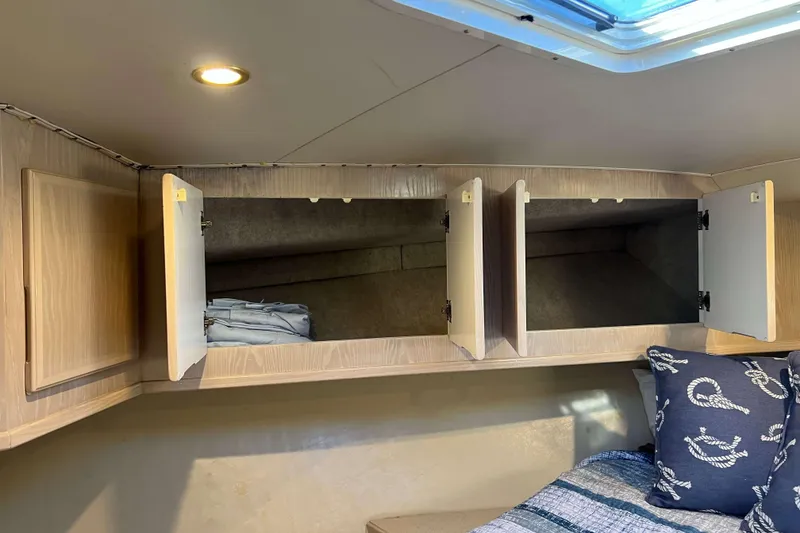 Slide: The Image of 2003 Henriques Yachts 35 Sportfisherman cabin with open storage and nautical-themed bedding. - 52