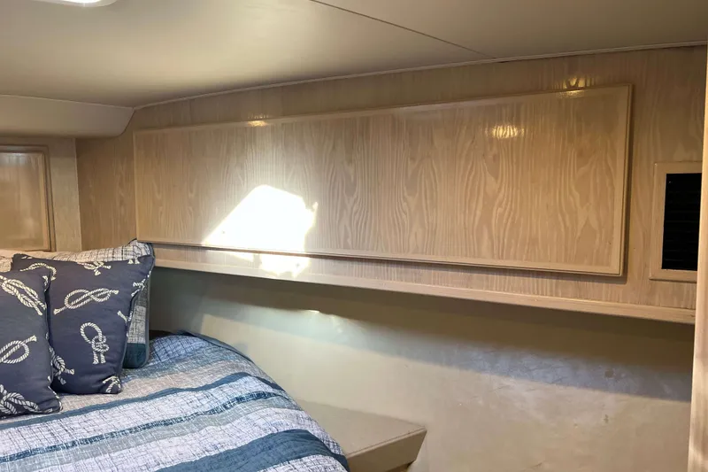Slide: The Image of 2003 Henriques Yachts 35 Sportfisherman cabin with wood paneling and nautical-themed bedding. - 55
