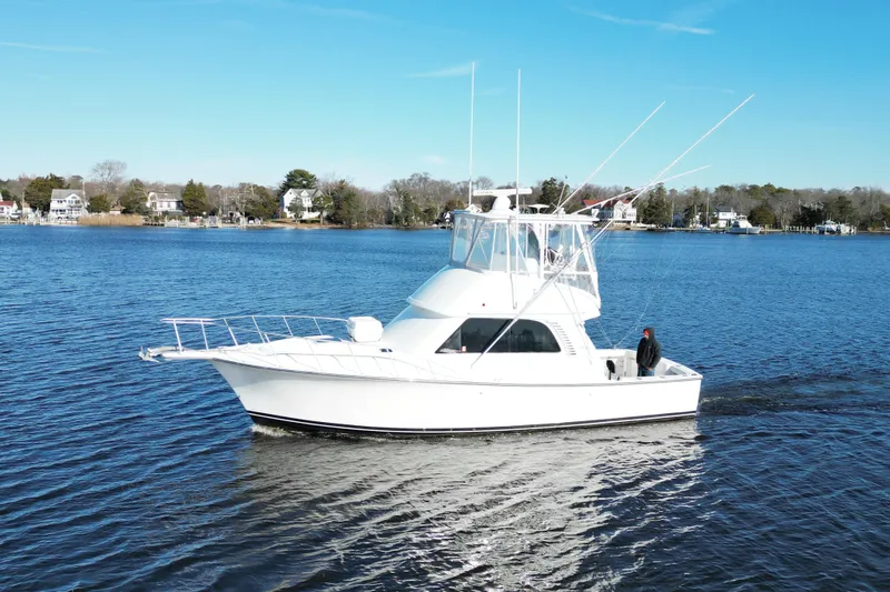 Slide: The Image of 2003 Henriques Yachts 35 Sportfisherman cruising on a serene lake under a clear blue sky. - 99