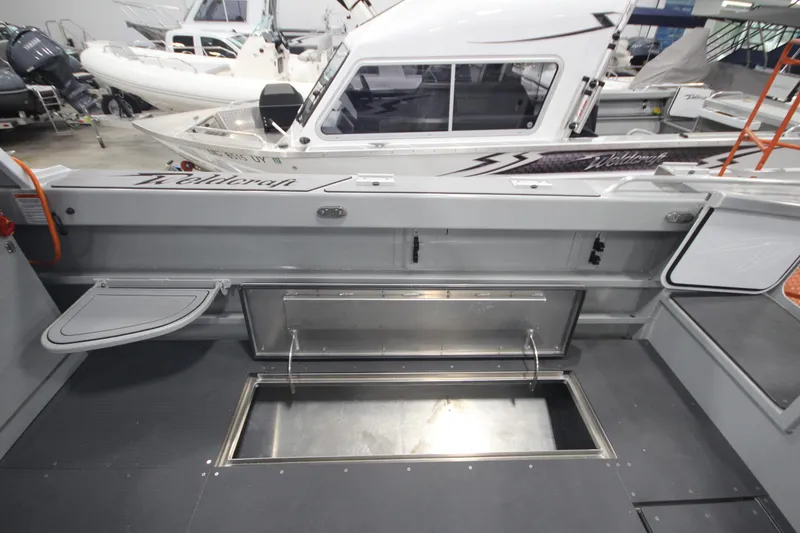 Slide: The Image of 2025 Weldcraft 300 Cuddy King OS boat interior with storage compartments and custom features. - 16