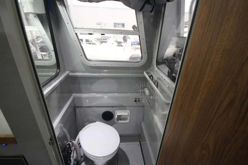 Slide: The Image of Interior of 2025 Weldcraft 300 Cuddy King OS boat bathroom with toilet and windows. - 24