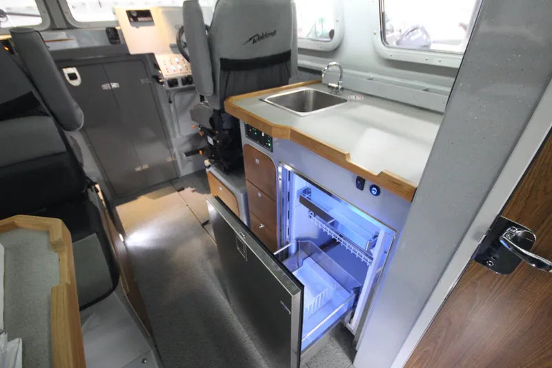 Slide: The Image of Interior of 2025 Weldcraft 300 Cuddy King OS, featuring kitchenette with sink and fridge. - 25