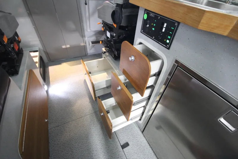 Slide: The Image of Interior of 2025 Weldcraft 300 Cuddy King OS, featuring storage drawers and control panel. - 29
