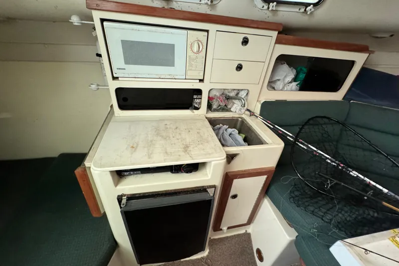 Slide: The Image of 1999 Albin 28 Tournament Express cabin with kitchenette, microwave, and fishing gear. - 12