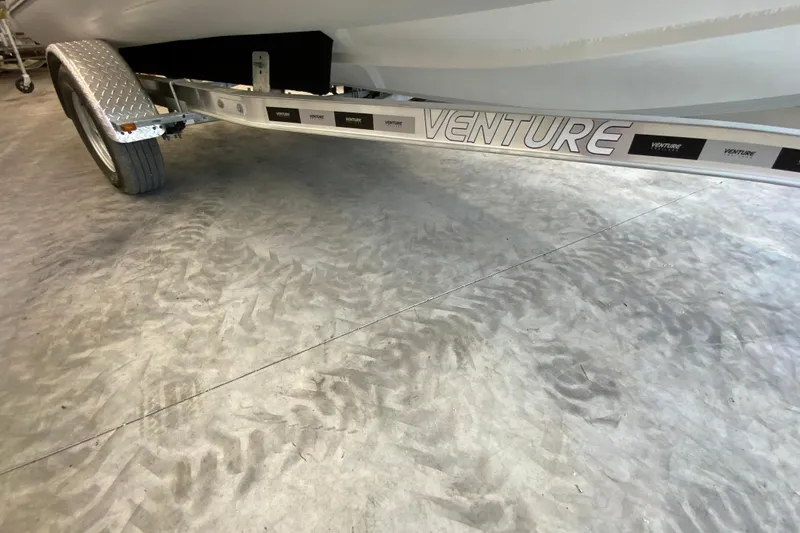 Slide: The Image of Trailer with "Venture" branding under a Gala V500 boat, 2026 model, on textured flooring. - 16
