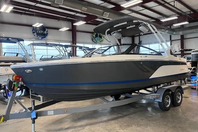 The Image of 2025 Cobalt CS23 Surf boat in showroom, gray and white design on trailer. - 0