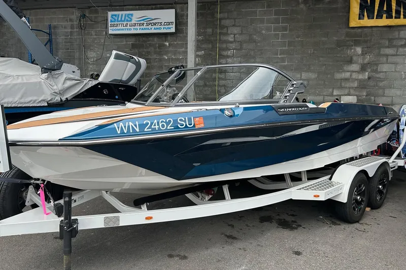 The Image of 2019 Nautique Ski Nautique boat on trailer, blue and white design, parked at Seattle Water Sports. - 1