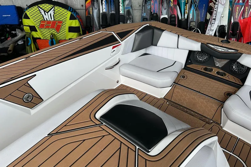 Slide: The Image of 2019 Nautique Ski Nautique interior with tan and white seating, surrounded by water sports gear. - 10