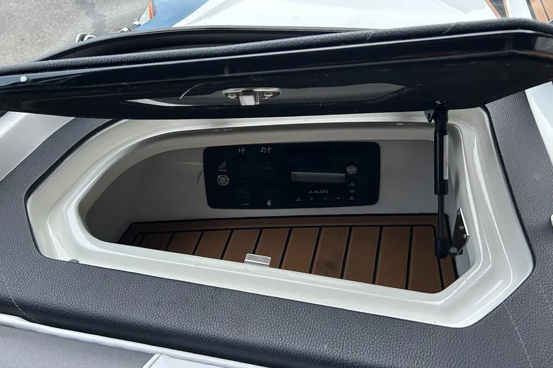 Slide: The Image of 2019 Nautique Ski Nautique boat compartment with JL Audio system and wooden flooring. - 19