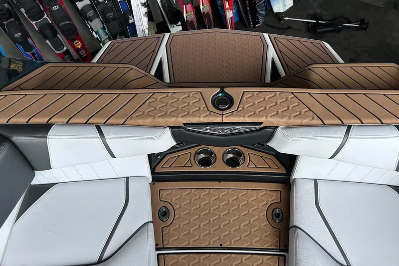 Slide: The Image of 2019 Nautique Ski Nautique interior with tan and white upholstery, featuring cup holders and storage. - 24
