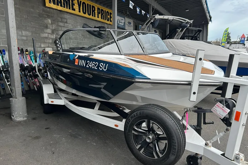 Slide: The Image of 2019 Nautique Ski Nautique boat on trailer, displayed at dealership with water skis nearby. - 5