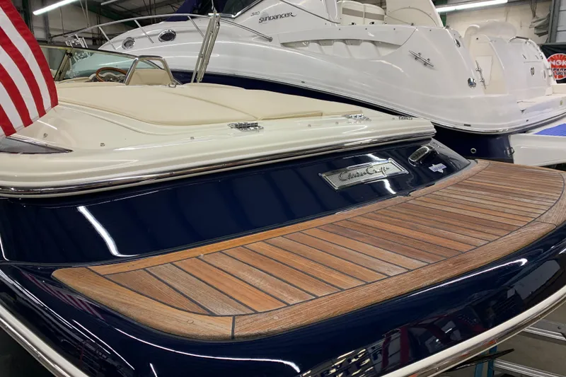 Slide: The Image of 2018 Chris-Craft Launch 23 boat with wooden deck and American flag in showroom. - 21