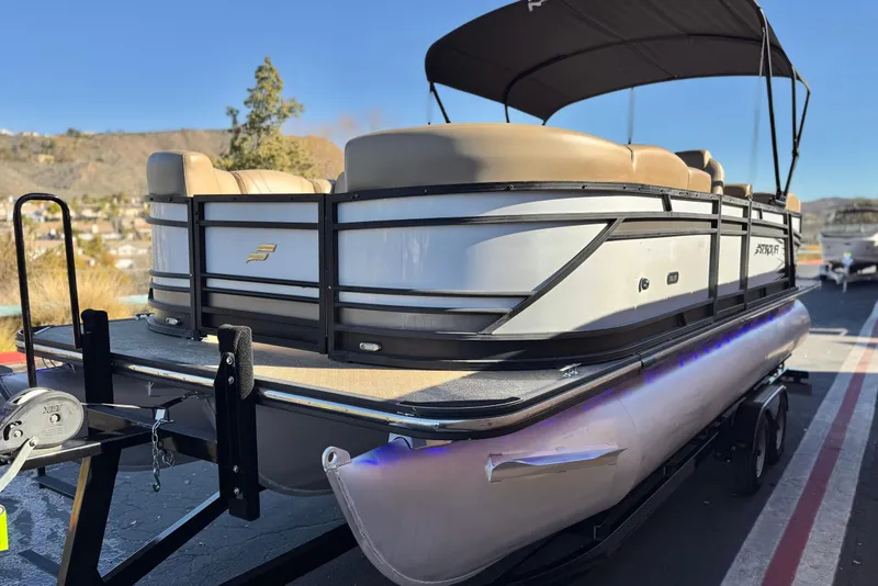 Slide: The Image of 2021 Starcraft SLS 3 pontoon boat on trailer, featuring beige seating and black canopy. - 3