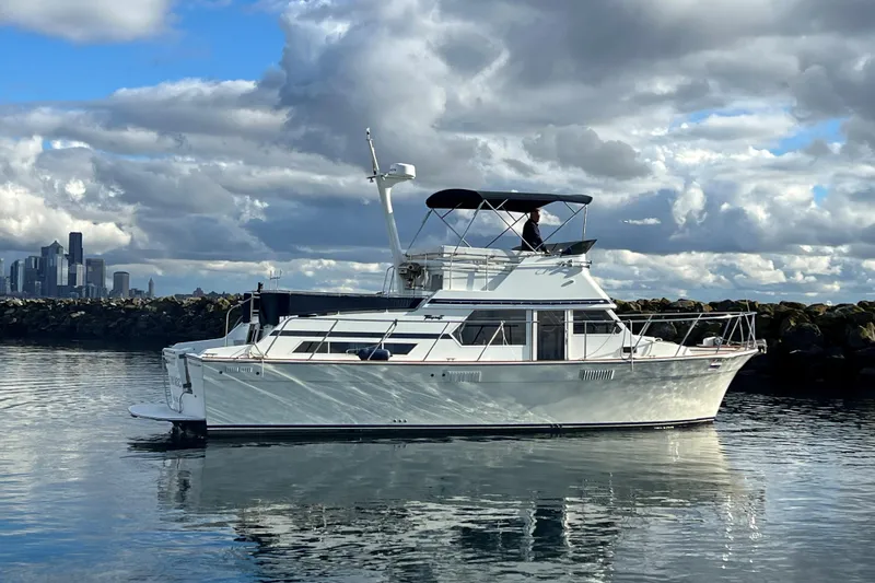 The Image of 1974 Tollycraft 40 Tri-Cabin MY yacht on calm water with city skyline backdrop. - 0