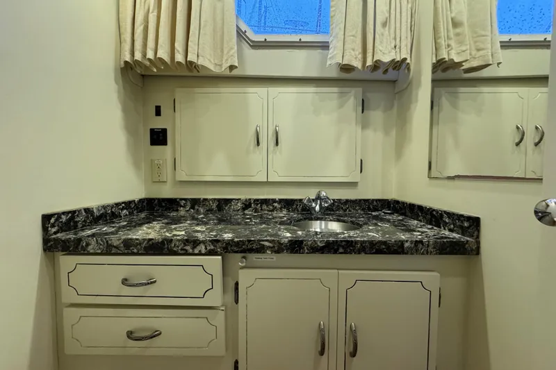 Slide: The Image of 1974 Tollycraft 40 Tri-Cabin MY bathroom with marble countertop and storage cabinets. - 14