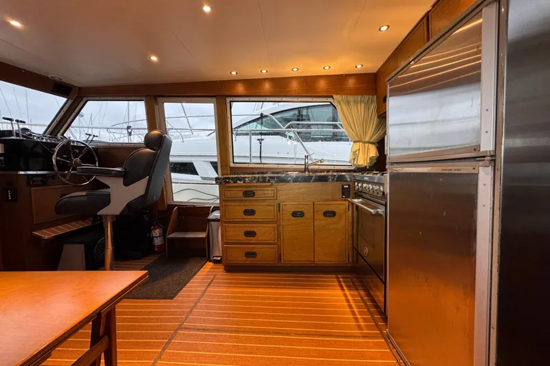 Slide: The Image of 1974 Tollycraft 40 Tri-Cabin MY interior with helm, kitchen, and wooden cabinetry. - 5