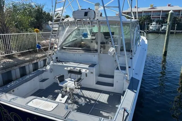 Slide: The Image of 2000 Cabo 45 Express boat docked, featuring spacious deck and fishing equipment. - 62