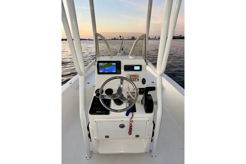 Slide: The Image of 2014 Pathfinder 2200 TRS boat console with steering wheel and navigation system on calm water. - 14