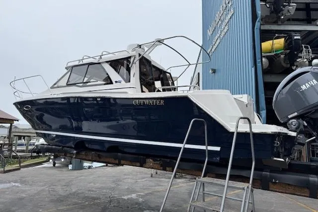 Slide: The Image of 2026 Cutwater C-248 Coupe boat at a marina, blue hull, docked for service. - 6