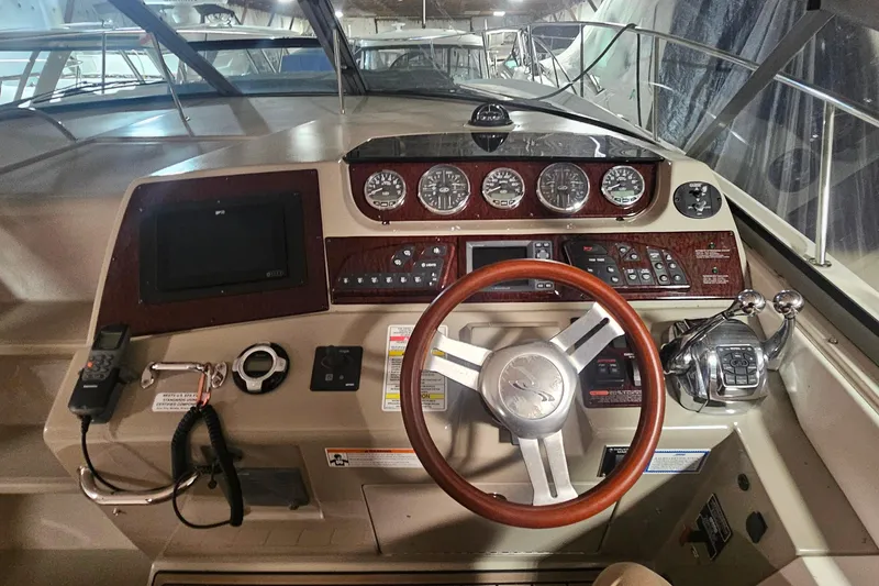 Slide: The Image of 2012 Sea Ray 370 Sundancer helm with gauges, controls, and wooden steering wheel. - 11