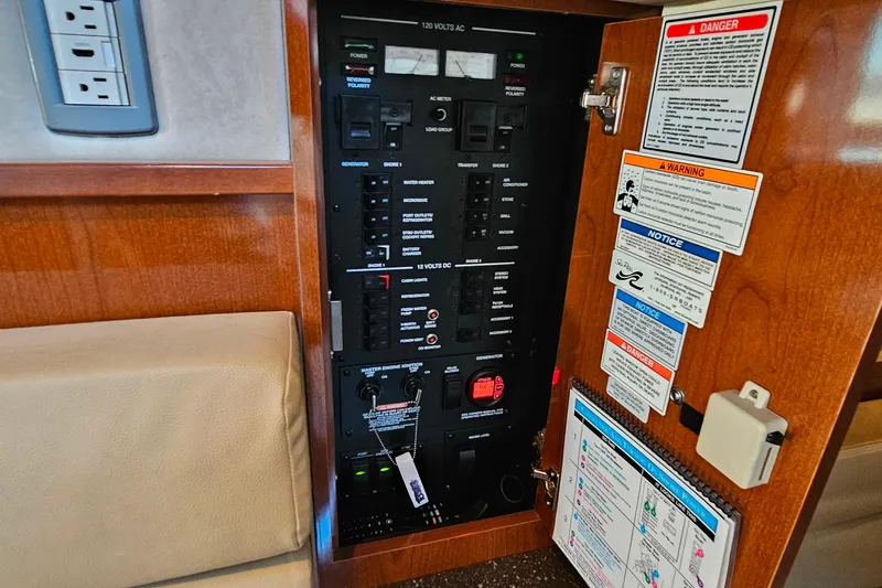 Slide: The Image of Electrical panel inside a 2012 Sea Ray Sundancer 370 boat, featuring various controls and safety notices. - 38