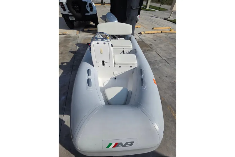Slide: The Image of 2014 AB Inflatables 10 VSX boat on concrete surface, featuring seating and steering console. - 2