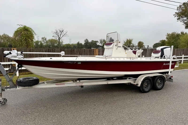 The Image of 2003 Blazer 2220 Bay boat on trailer, red and white design, parked on roadside. - 1